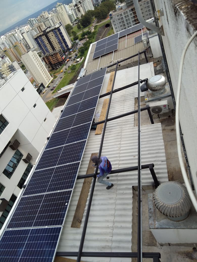 Cobertura de prédio urbano com fileira de painéis solares em estrutura metálica
