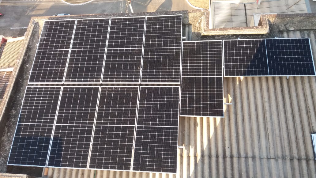 Vista de cima de telhado de fibrocimento com grande arranjo de painéis solares